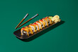 Contemporary still life of maki sushi with salmon, curry sauce, and tobiko roe on black plates against a deep green background