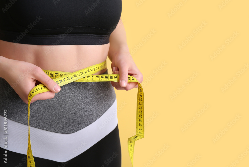 Young woman with measuring tape on beige background, closeup. Diet concept