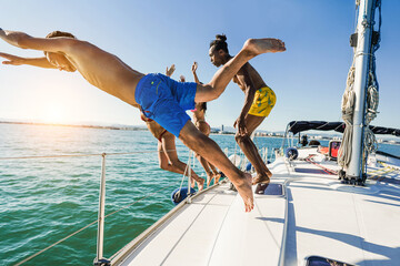 Wall Mural - Happy friends diving from sailing boat into the sea - Soft focus on front guy face