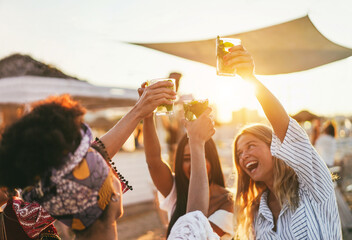 Multiracial happy friends cheering and drinking mojitos at beach party - Focus on left hand holding cocktail