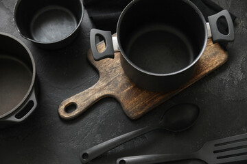 Cooking pots and kitchen utensils on dark background