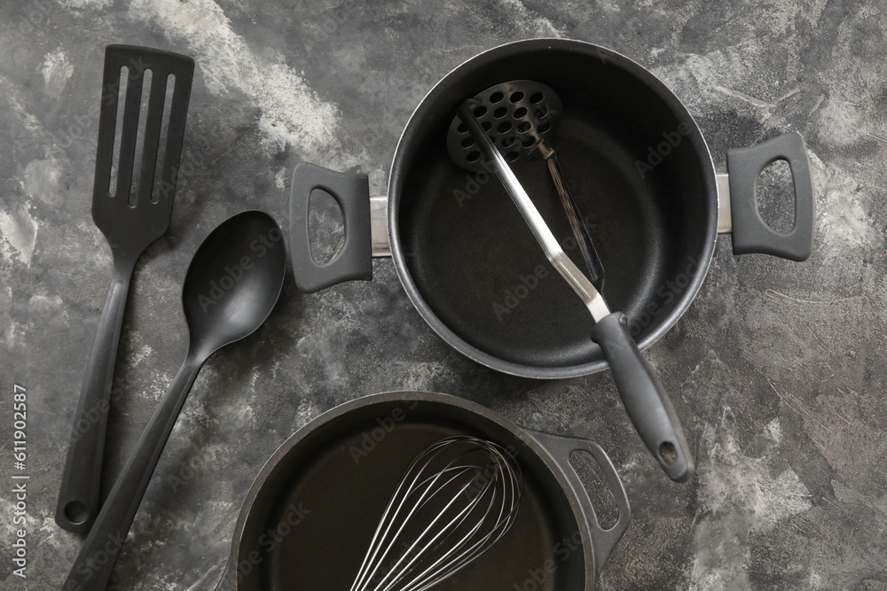 Cooking pots and kitchen utensils on dark grunge background
