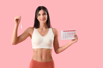 Wall Mural - Young woman with tampon and menstrual calendar on pink background