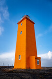 Fototapeta Pomosty - orange icelandic lighthouse view with beutiful clouds