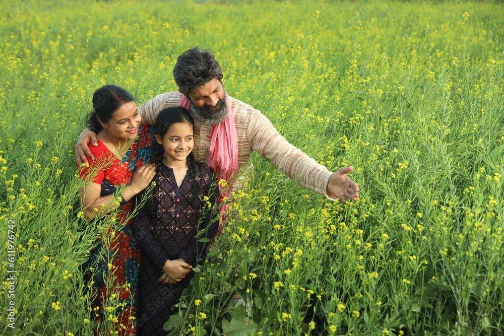 Happy Indian farmers family standing in mustard field in day time ...