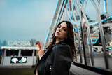 Fototapeta Młodzieżowe - portrait of a young confident beautiful woman model in luna park posing wearing black leather jacket fashion 