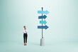 © Who is Danny - Right decision and choice concept with pensive businesswoman looking at signpost with blue arrows in different direction on abstract light background