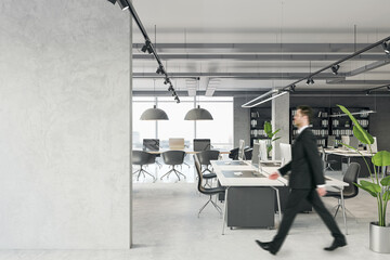 Wall Mural - Blank grey concrete wall with empty space for poster or image frame in a corridor of modern loft office interior and walking person, mockup