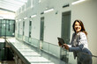 © BGStock72 - Young woman working on digital tablet in the office hallway