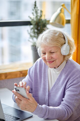 pretty elderly lady sit with laptop and smartphone, enjoying modern technologies. smiling aged woman, grandmother using laptop alone at home, retired people technology concept.