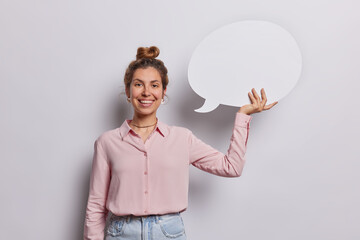 Wall Mural - Cheerful young woman holding communication bubble she invites your message to take center stage creating ideal setting to captivate audience with your brands story wears elegant shirt and jeans