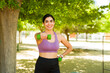 © AntonioDiaz - Latin sporty woman smiling exercising with dumbbell weights