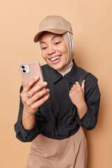 Wall Mural - joyful muslim woman captures delightful selfie using her smartphone with genuine smile she looks dir