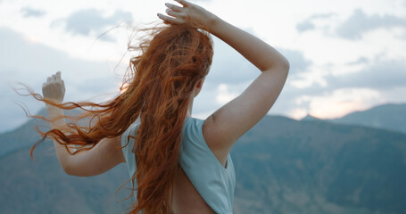 Sticker - Carefree girl with red hair raising her hands up to the wind, embracing freedom and tranquility, enjoying scenic view of mountains 