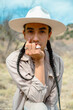 Fashionable queer Mexican native person in hat and jewelry outdoors in the desert