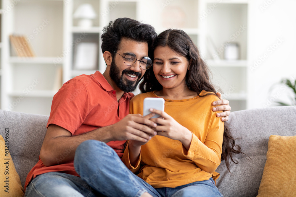 Young Smiling Indian Couple Using Mobile Phone And Embracing Together ...