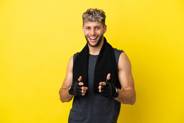 Canvas Print - Sport caucasian man isolated on yellow background pointing to the front and smiling