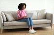 © Prostock-studio - Glad millennial african american curly lady typing on laptop on sofa, chatting in social networks in living room