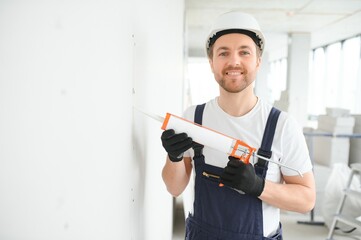 Wall Mural - Professional Workman Applying Silicone Sealant With Caulking Gun on the Wall