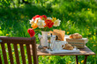 Bouquet of flowers, croissant, cup of tea or coffee, books on table in summer garden. Rest in garden, reading books, breakfast, vacations in nature concept. Summer time in garden on backyard