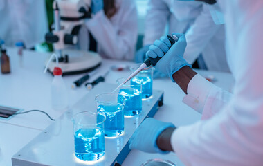 Close up of Scientists in Chemical Lab working with microscope, test tubes, and pipette.