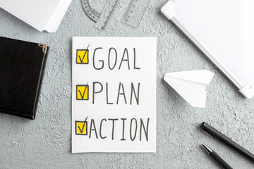 Wall Mural - above view of paper plane notebook ruler white sheet with goal plan action writing on gray sand back