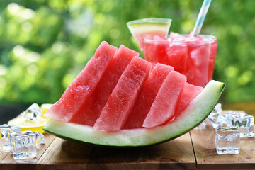 Wall Mural - A piece of decoratively sliced watermelon and drink on the table in the garden