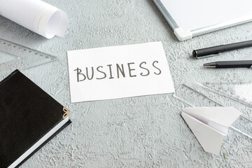 Wall Mural - overhead view of business writing on white sheet and black notebook paper plane pens ruler desk blan