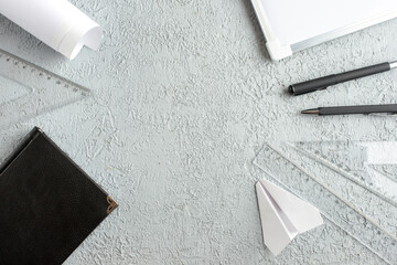Wall Mural - overhead view of free space on black notebook paper plane pens ruler desk blank on gray sand backgro