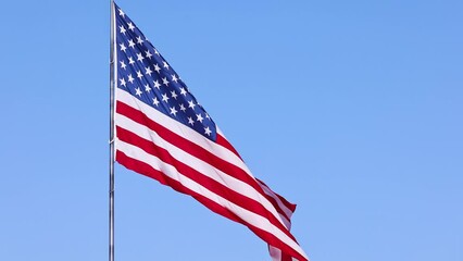 Wall Mural - us flag on a flagpole blowing in the breeze.