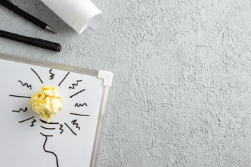 Wall Mural - top view of pens incompletely drawn thing and crushed wrapped paper on white desk on gray sand backg