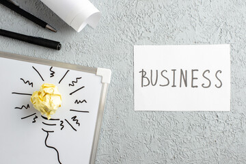 Wall Mural - top view of sheet with business writing incompletely drawn thing and crushed wrapped paper on white 