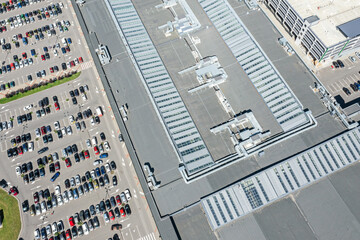 Wall Mural - shingle roof of shopping mall with ventilation system. parking lot with parked cars. aerial top view.