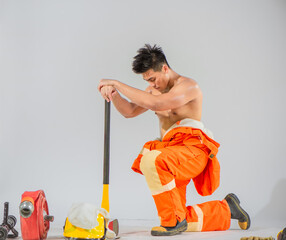 Wall Mural - Professional firefighter sits and kneels down holding an iron axe with his eyes closed indicating a moment of contemplation and mental preparation.