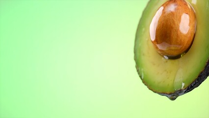 Canvas Print - Avocado oil pouring, dripping essential oil on cut avocado on light green background, slow motion. Fresh cut avocado with oil stream. Concept of healthy fruit for eating or cosmetics