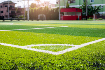 Artificial turf soccer field, a corner marker line, green background. Outdoor field.