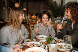 Fototapeta  - Group of friends drinking wine while dining in restaurant