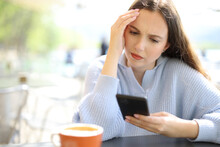 Worried Woman Checking Phone In A Restaurant Terrace