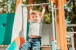© Westend61 - Boy hanging on slide in playground