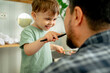 © Westend61 - Happy boy brushing teeth of father at home
