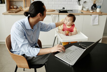 Freelancer Father Stroking Daughter Sitting On High Chair At Home