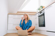 © Westend61 - Smiling woman drinking water sitting cross-legged with laptop in kitchen