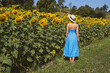 © Westend61 - Woman standing near sunflowers in field at sunny day