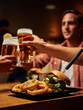 © StratfordProductions - Close-up of young multiracial friends in casual clothing enjoying fast food and beers at bar