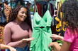 Pretty black woman selling colorful clothes to customer at flea market or fair