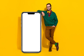 Wall Mural - Full size portrait of handsome guy demonstrate empty space big telephone screen isolated on yellow color background