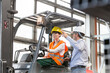© KOTO - Supervisor directing worker driving forklift in factory