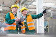 © KOTO - Workers in protective workwear talking with clipboard in factory