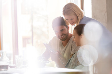 Family using digital tablet in sunny cafe