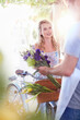 Florist placing flowers in basket on woman‚Äôs bicycle